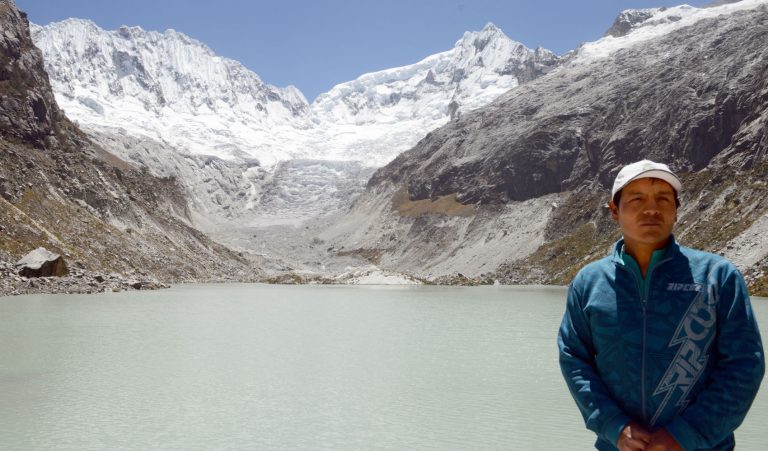 Saul Luciano em frente ao lado e ao pico ameaçados pelas mudanças climáticas