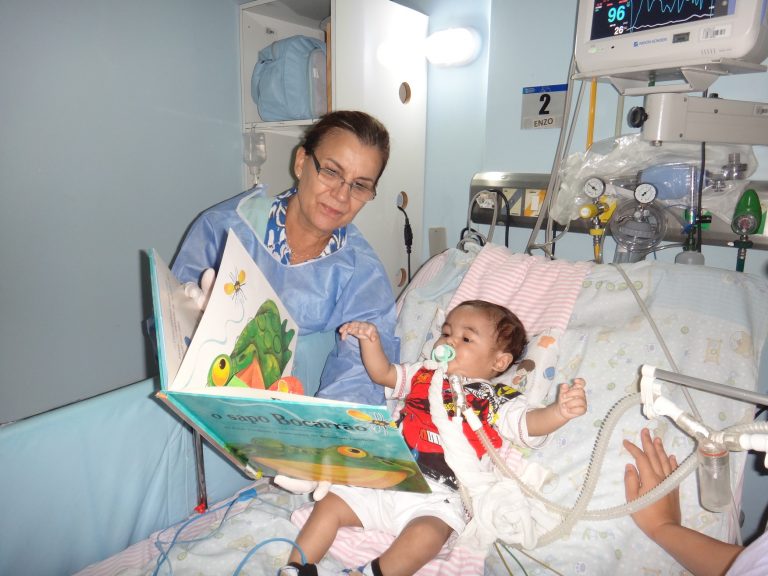 Voluntária mostra as figuras do livro para o bebê internado. Foto Divulgação