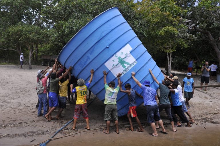 Ribeirinhos da comunidade de Anumã, no Tapajós, carregam caixa d'agua comunitária (Foto Chico Ferreira/Divulgação)