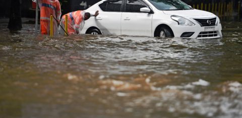 Funcionários da Comlurb tentam desobstruir os bueiros com as ruas da cidade alagadas. Foto Carl de Souza/AFP