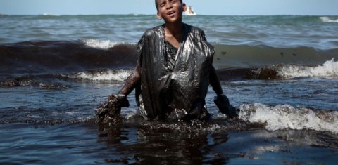 Voluntário no trabalho de limpeza das praias em Cabo de Santo Agostinho (PE), adolescente sai do mar coberto de óleo: 200 localidades atingidas em todo o Nordeste (Foto: Leo Malafaia/AFP)
