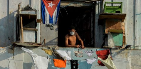 Homem usa máscara facial na varanda em Havana. As autoridades cubanas dizem que o embargo econômico dos EUA vem dificultando o combate à covid-19. Foto Yamil Lage/AFP