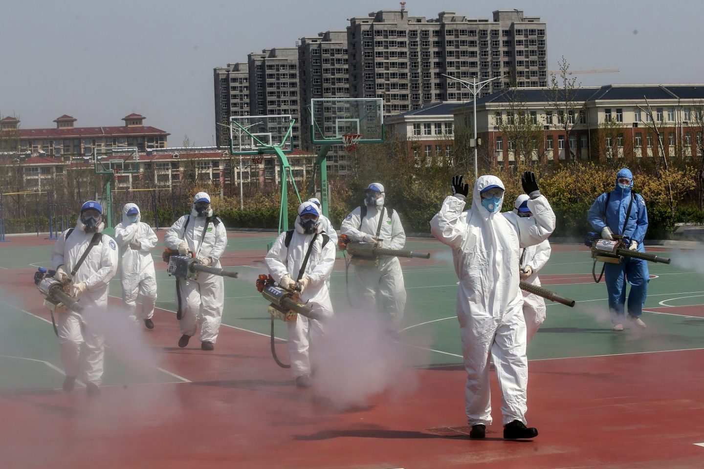 Voluntários desinfetam as quadras esportivas das escolas que se preparam para reabrir na província de Shandong, na China. Foto STR/AFP/China Out