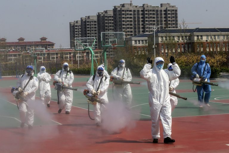 Voluntários desinfetam as quadras esportivas das escolas que se preparam para reabrir na província de Shandong, na China. Foto STR/AFP/China Out