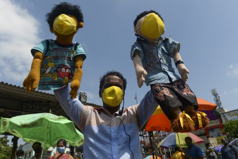 Um apresentador de marionetes, com seus fantoches mascarados, tenta conscientizar as pessoas que passam por Chennai, na Índia. Foto Arun Sankar/AFP