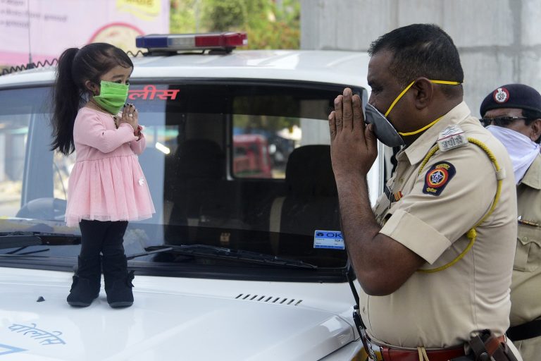 Jyoti Amge, a menor mulher do mundo, segundo o Guinness, cumprimenta um policial em Naqpure, na Índia, enquanto apela aos cidadãos do país para ficarem dentro de suas casas. Foto STR/AFP