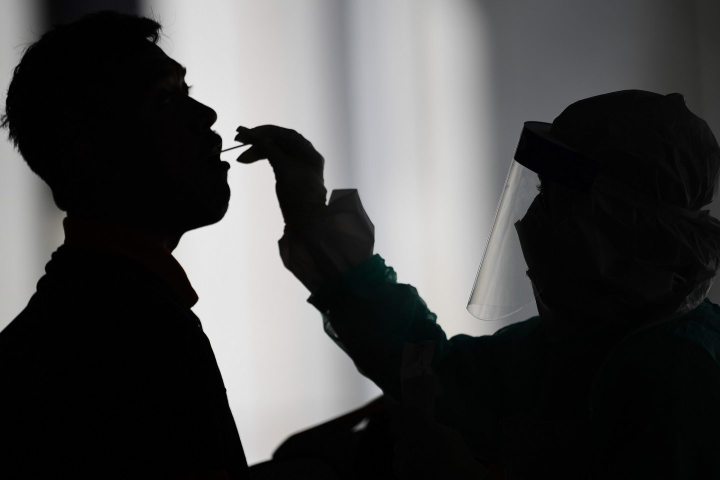 Profissional de saúde usa um swab para coletar uma amostra para o teste de coronavírus de um homem em Gombak, nos arredores de Kuala Lumpur, na Malásia. Foto Mohd Rasfan / AFP)