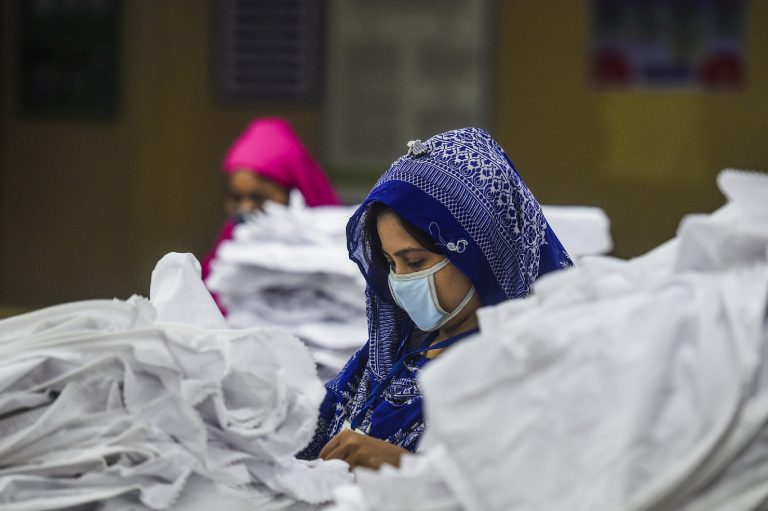 Mulheres usando máscaras trabalham em uma fábrica de roupas durante o bloqueio imposto pelo governo de Bangladesh como medida preventiva contra a propagação da covid-19. Foto Munir Uz Zaman/AFP
