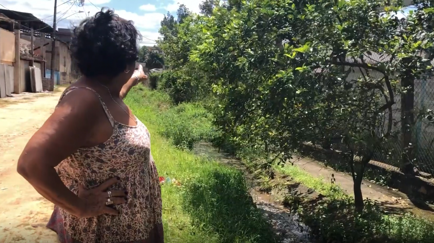 A dona de casa Maria de Fátima de Souza mostra o esgoto a céu aberto em Campos Elíseos: associação de moradores calcula que 80% das ruas do distrito não tem saneamento básico (Reprodução)