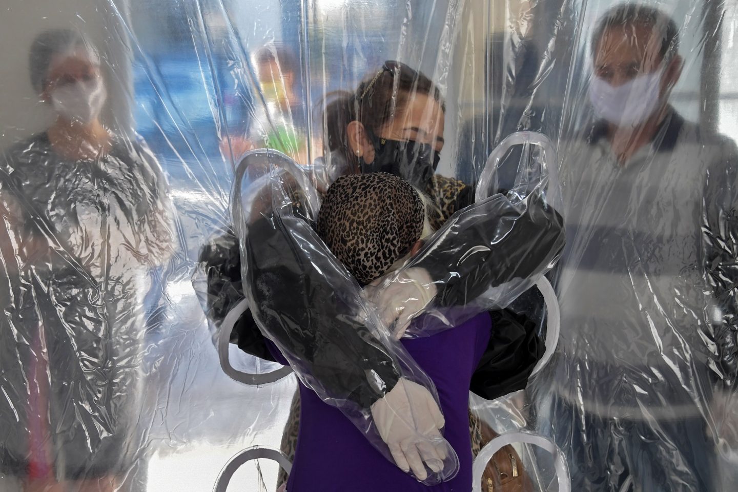 Elisabete Nagata (em cima) abraça sua cunhada Luiza Nagata, de 76 anos, através de uma cortina de plástico transparente em um lar de idosos em São Paulo. Foto Nelson Almeida/AFP