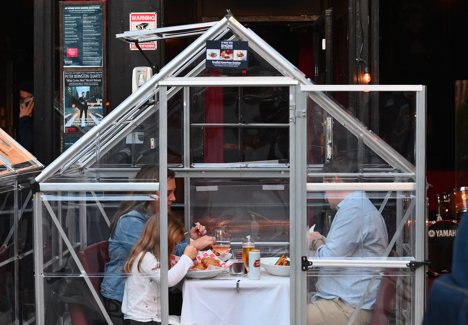 Em um restaurante em Manhattan, Nova York, pessoas jantam em barracas plásticas improvisadas para garantir o distanciamento social. Foto Angela Weiss/AFP