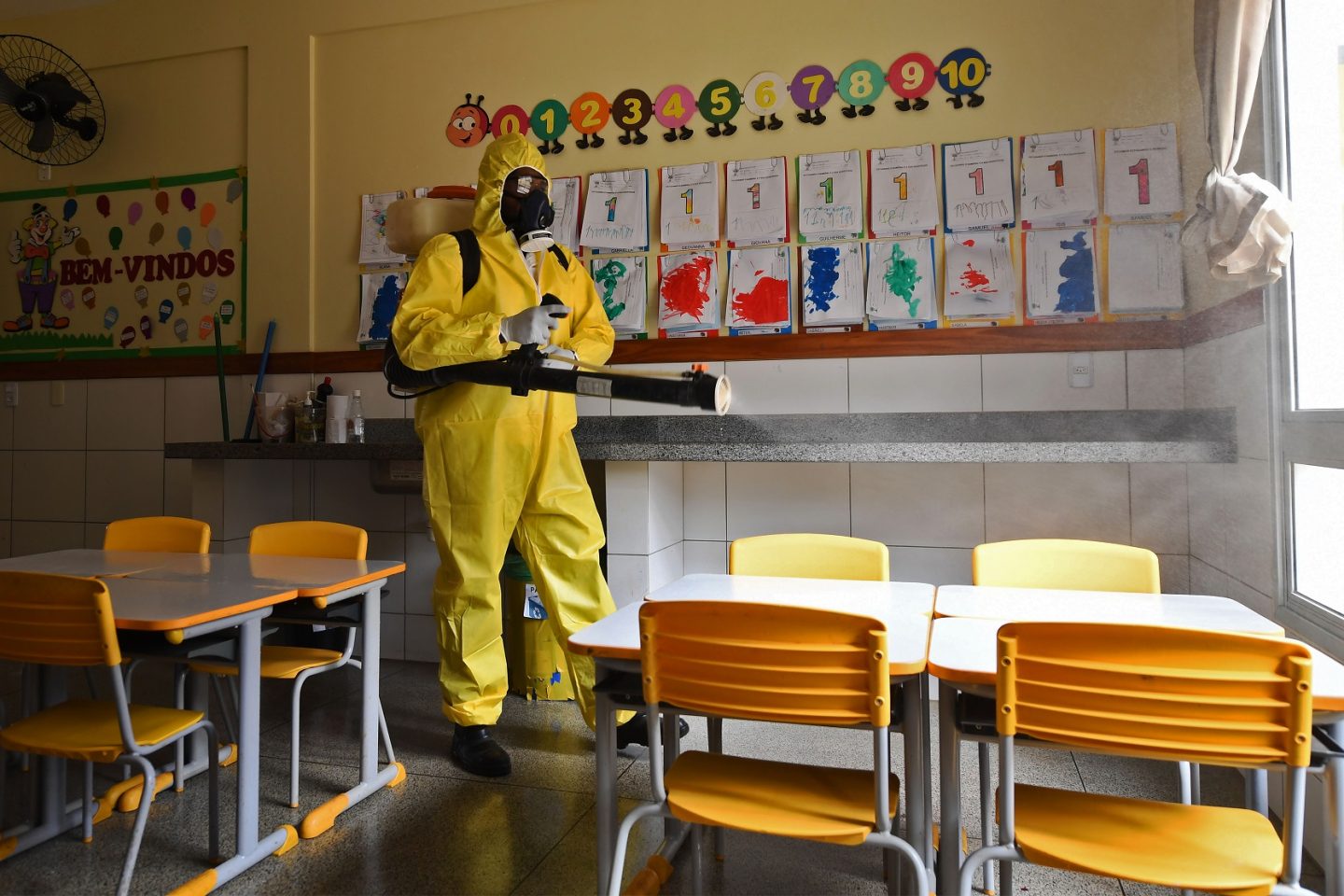 Funcionário do governo do Distrito Federal desinfeta uma escola pública como medida preventiva contra a disseminação da covid-19. Foto Evaristo Sá/AFP