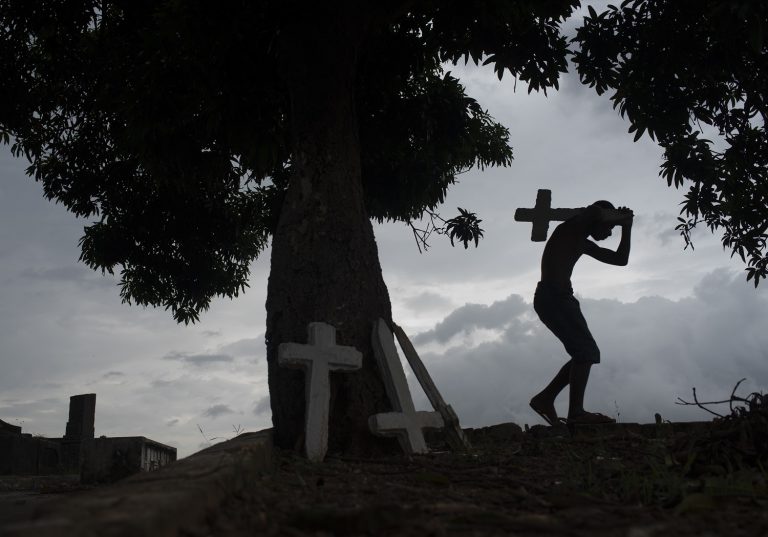 Jovem trabalha em um cemitério do Rio, pintando cruzes, limpando túmulos e correndo risco de contaminação. Foto Fabio Teixeira/NurPhoto - Julho de 2020