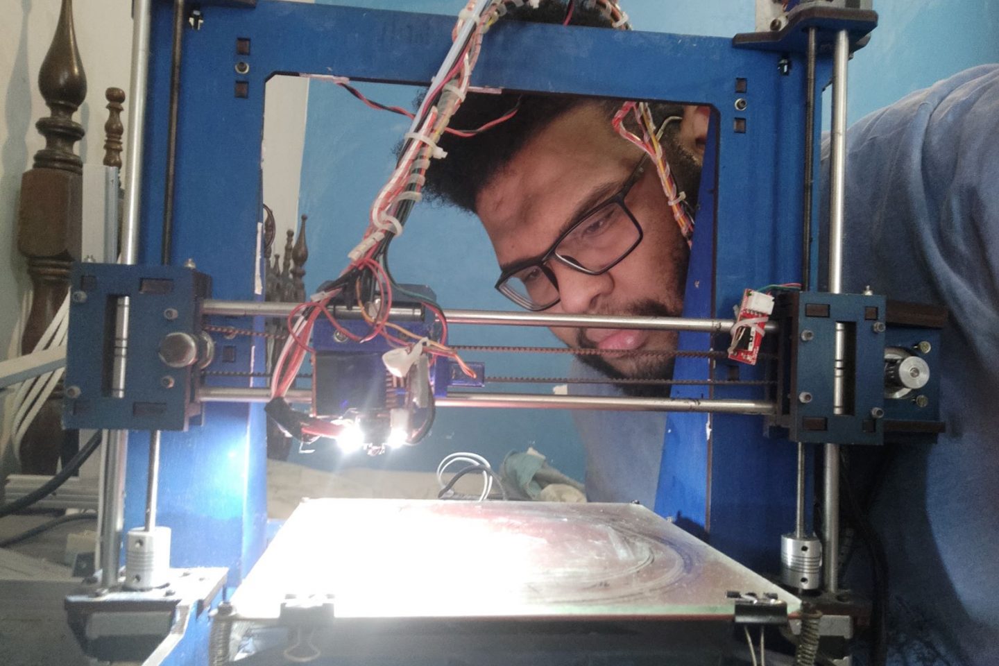 Lucas confere sua impressora 3D feita de sucata eletrônica: máscaras face-shield para unidades da saúde da área Alemão (Foto: Divulgação)