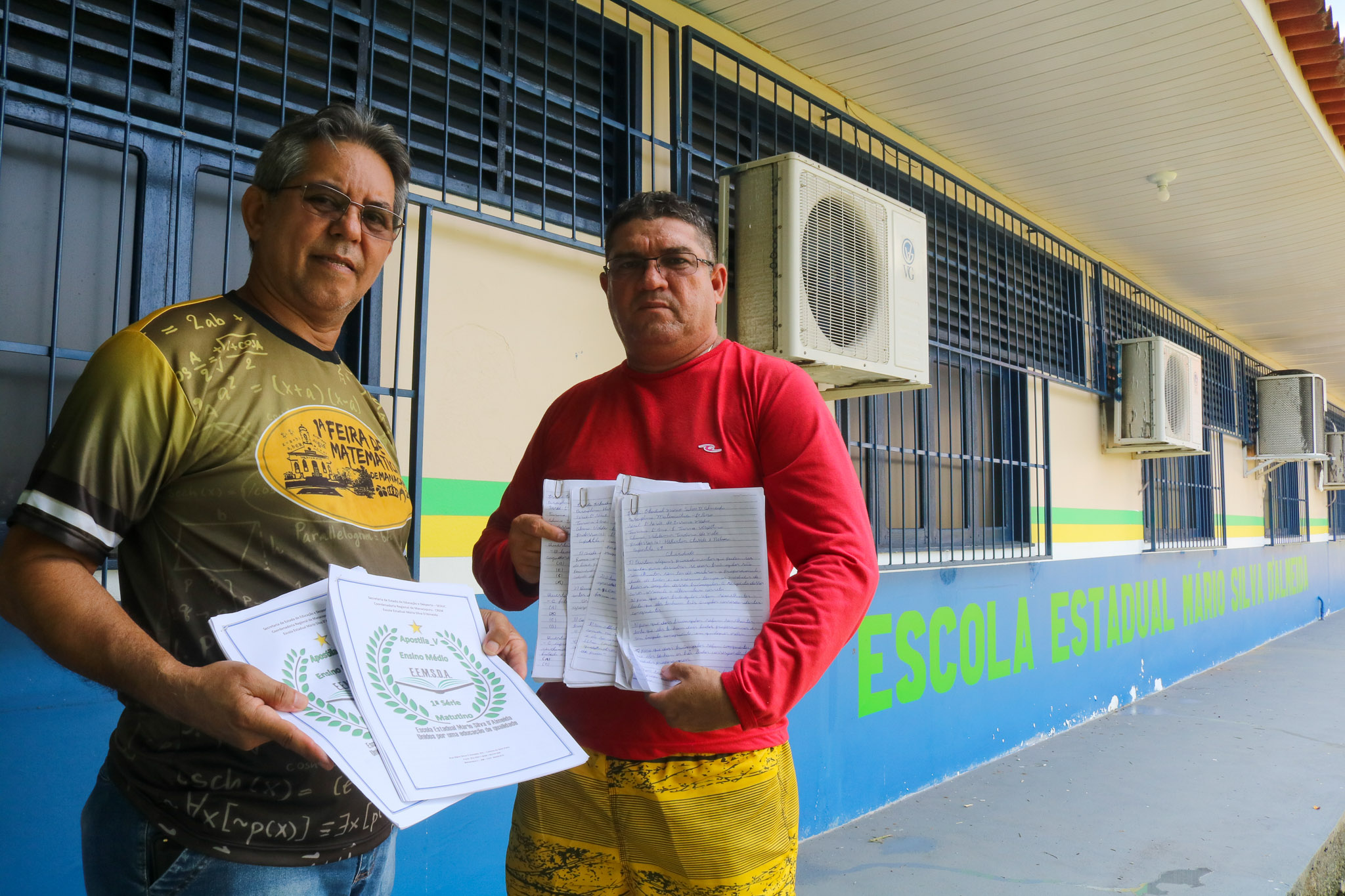 O professor Hayrson (à direita) com o gestor Mackson e as apostilas: entregador de apostilas com aulas improvisadas nas comunidades isoladas (Foto: Bruno Tadeu)
