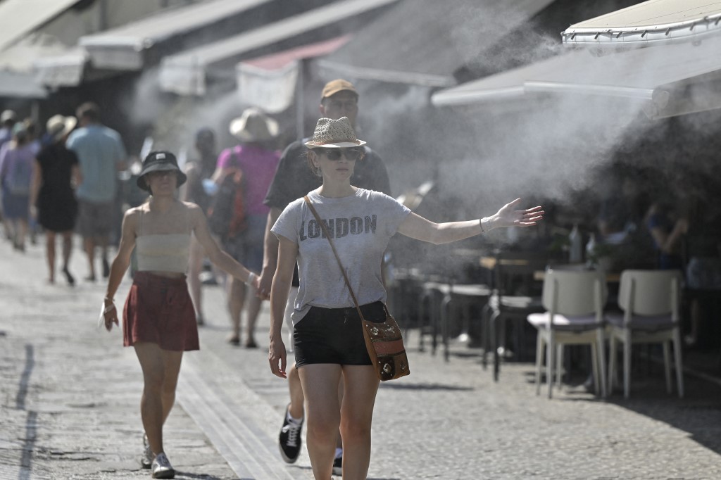 Turistas aproveitam spray de água para enfrentar o calor em Atenas: temperatura na Grécia alcançou 44 graus (Foto: Louisa Gouliamaki / AFP - 29/07/2021)