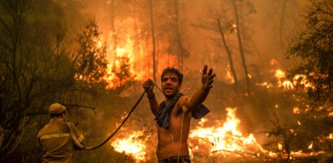 Morador ajuda bombeiro no combate ao incêndio na ilha grega de Eubeia, que arde desde o primeiro dia de agosto: países ricos não cumprem promessas de financiamento climático (Foto: Angelos Tzortzinis / AFP)
