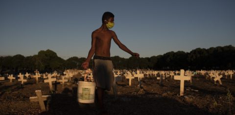 Jovem trabalha em um cemitério do Rio, limpando túmulos e pintando cruzes. Demanda cresceu com a pandemia, que tirou a vida de mais de 605 mil brasileiros. Foto Fabio Teixeira/Anadolu Agency/AFP. Outubro/2021
