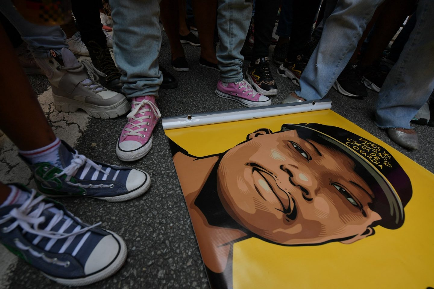 Amigos se reúnem em torno de um cartaz durante um protesto contra o assassinato do refugiado congolês de 24 anos Moise Kabagambe. Foto Nelson Almeida/AFP