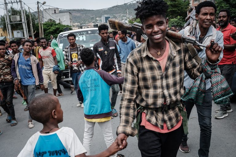 Um combatente da Frente de Libertação Popular de Tigré (TPLF) aperta a mão de um menino enquanto soldados são recebidos por pessoas em uma rua em Mekele, capital da região. Foto Yasuyoshi Chiba/AFP