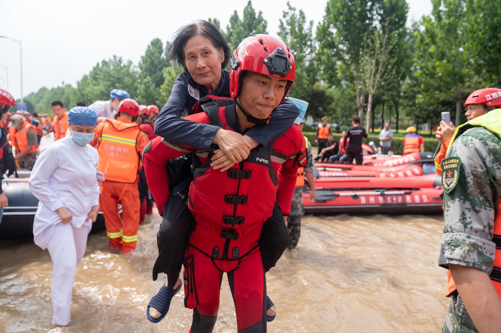 Integrante de equipe resgate retira paciente de hospital alagado em Zhengzhou, na província de Henan: mais de 300 mortos (Foto: Cai Yang / Xinhua / AFP - 22/07/2021)