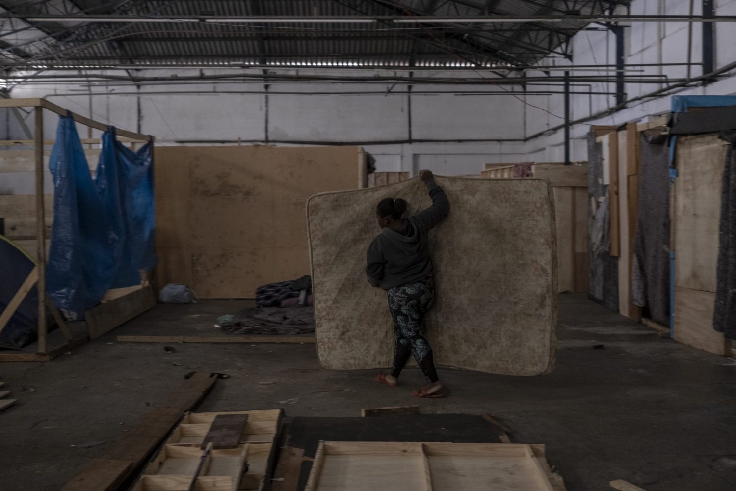 Mariana coloca seu colchão no espaço reservado para sua família em um acampamento em São Paulo. Ela economiza para pagar a estrutura de compensado. Foto Dan Agostini/Diálogo Chino