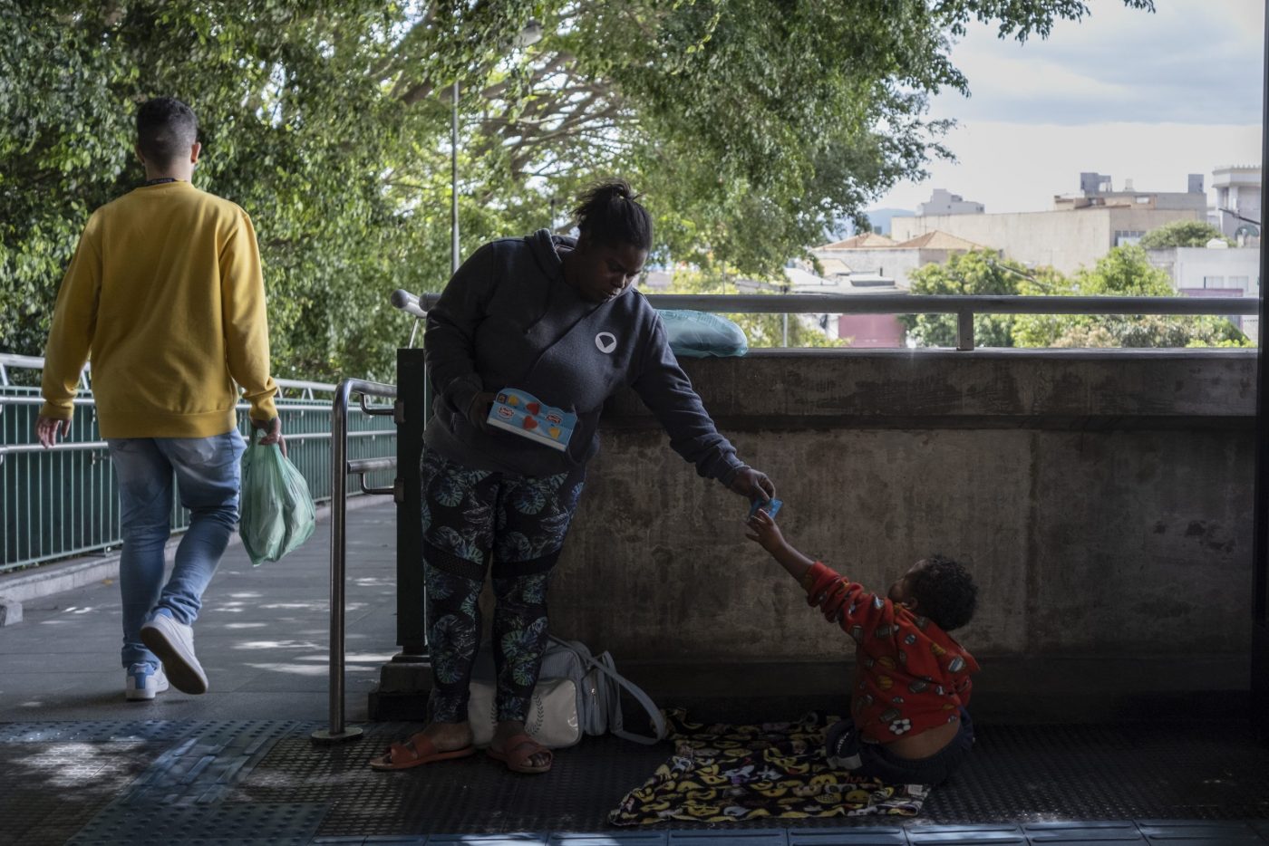 Mariana e Kaleb na estação do metrô onde ela vende doces. Muitas pessoas pagam pelos doces mas não os levam, por isso muitas vezes sobram pacotes no final do dia para ela e seus filhos. Foto Dan Agostini/Diálogo Chino