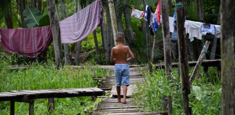 Menino atravessa ponte de madeira na Porto do Ceasa: série Cidade Invisível, da Netlflix da visibilidade à comunidade ribeirinha em Belém sem acesso às redes de água, esgoto e energia (Foto: João Paulo Guimarães)