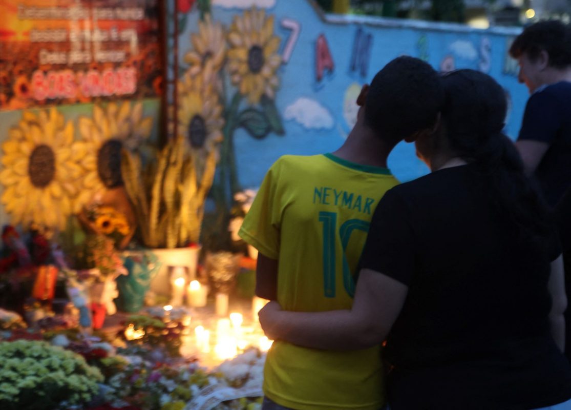 Mãe ampara filho na vigília na frente da creche onde crianças foram assassinadas: violência muda rotina das escolas de todo o país (Foto: Anderson Coelho / AFP - 06/04/2023)
