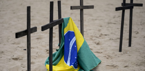 Uma bandeira brasileira é vista ao lado de uma cruz enquanto ativistas da ONG Rio de Paz e parentes prestam homenagem a Marcio Antonio, que foi a cara do luto do Covid-19 no Brasil e morreu aos 58 anos, no final de 2022. Foto Mauro Pimentel/AFP