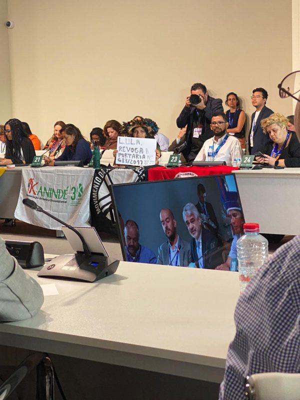 Em reunião com o presidente na COP28, em Dubai, Txai Paiter Suruí segura uma placa pedindo providências do governo. Foto Raylson Santos