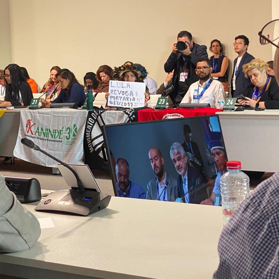 Em reunião com o presidente na COP28, em Dubai, Txai Paiter Suruí segura uma placa pedindo providências do governo. Foto Raylson Santos