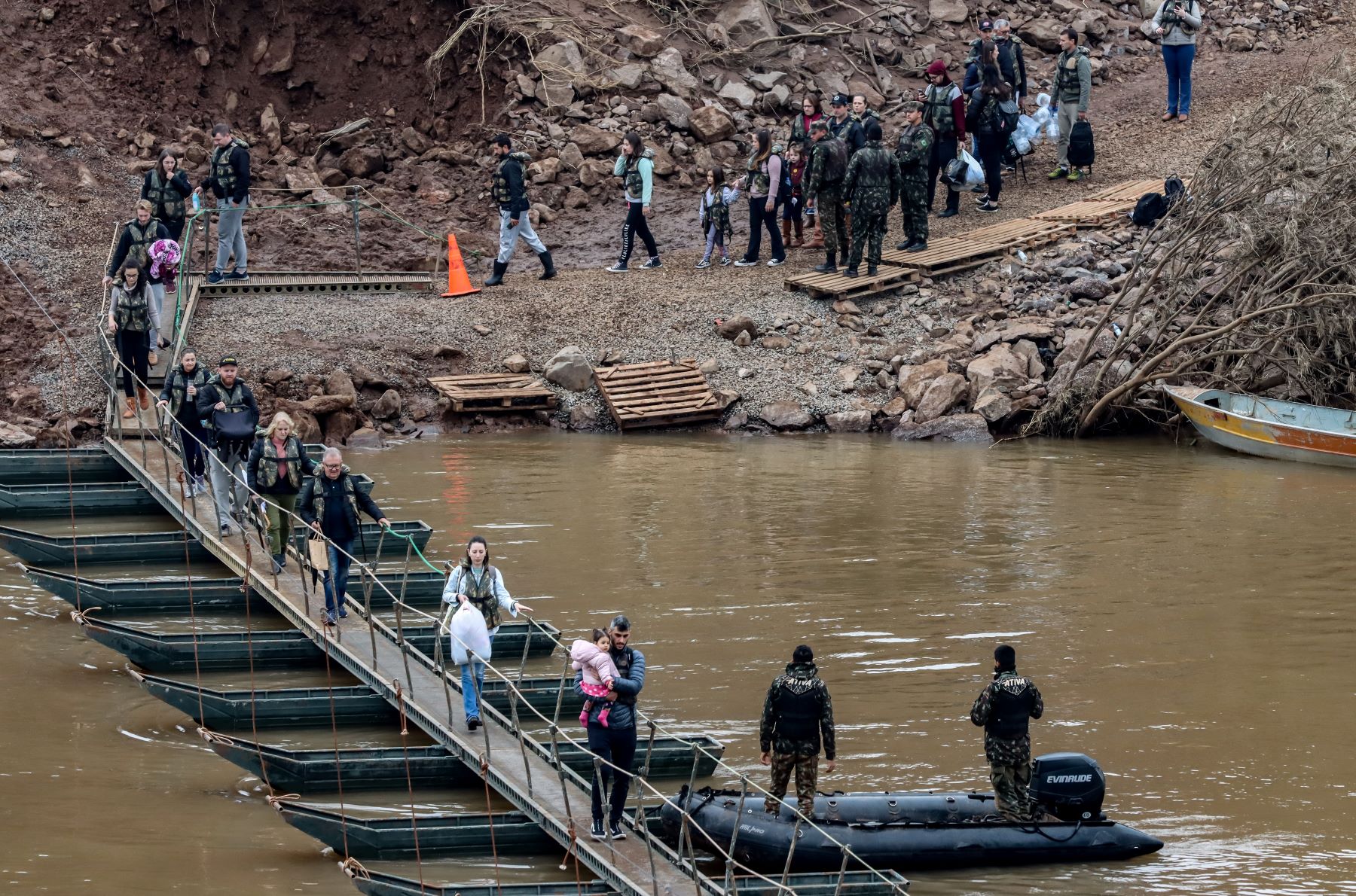 Pessoas atravessam passarela flutuante sobre afluente do Taquari, ligando as cidades de Lajeado a Arroio do Meio: moradores pretendem mudar de cidade; prefeituras estudam mudar bairros de lugar (Foto: Rafa Neddermeyer / Agência Brasil)