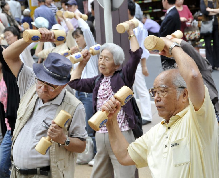 Idosos se exercitam com halteres de madeira no terreno de um templo em Tóquio, para celebrar o Dia do Respeito ao Idoso no Japão. Pessoas de 50 anos e mais já representam metade da população do país. Foto Yoshikazu Tsuno/AFP