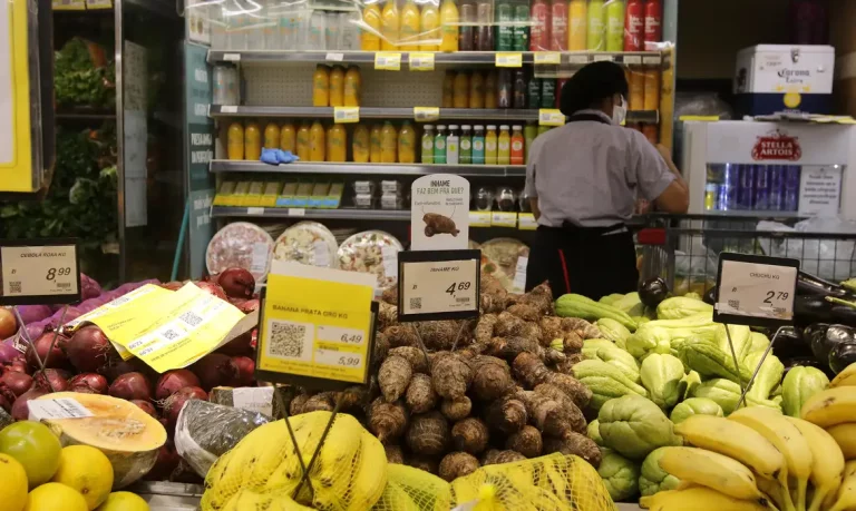 Foto colorida de supermercado no Rio de Janeiro. Na imagem aparecem diferentes alimentos, principalmente frutas em cima de uma bancada