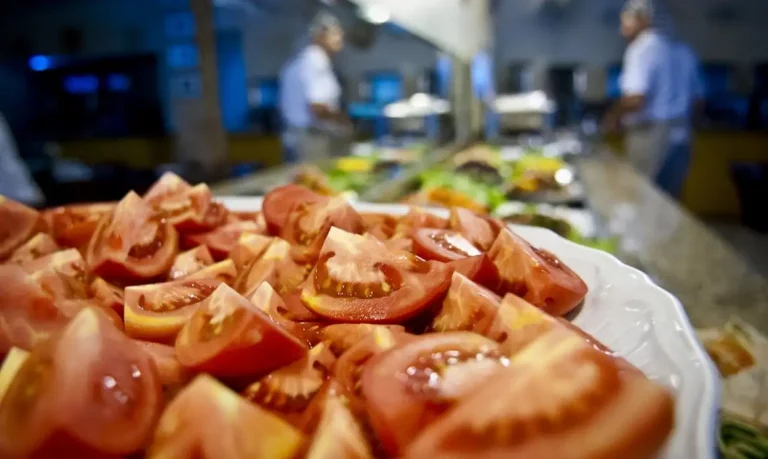 Foto colorida de mesa com tomate e outros alimentos ao fundo