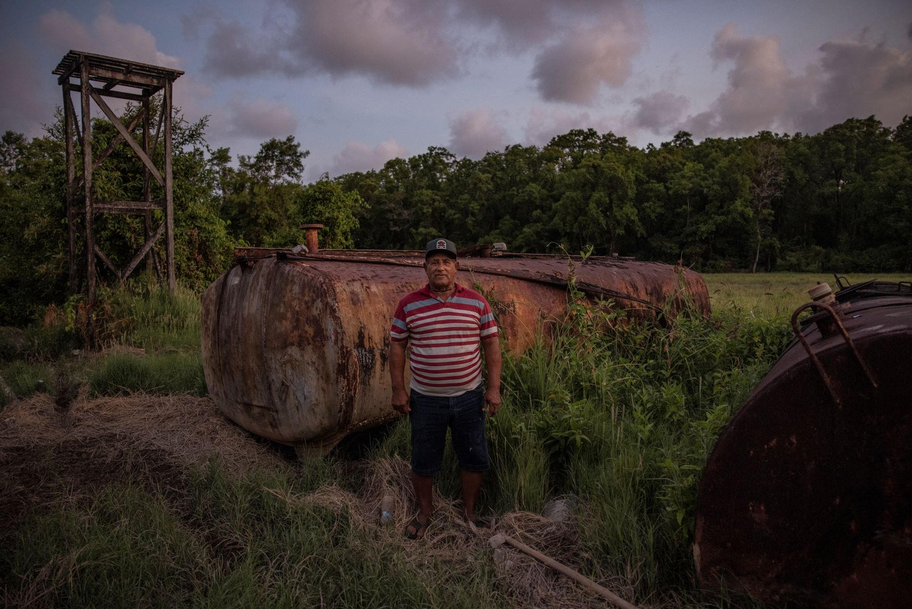 Amiraldo Ferreira, pescador e um dos moradores mais antigos de Sucuriju, ao lado de tanques de combustível abandonados na comunidade: interesse na exploração da margem equatorial meio século atrás (Foto: Victor Moriyama / InfoAmazonia)