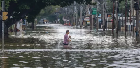Foto colorida de pessoa em meio às enchentes em Porto Alegre, no Rio Grande do Sul