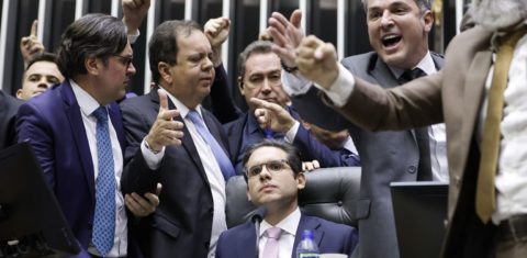 Foto colorida que mostra o deputado Hugo Motta, sentado no plenário da Câmara e cercado por deputados da direita; bancada ruralista se articulou para atacar legislação ambiental