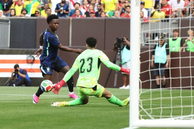 Foto colorida de cena da partida de futebol entre Brasil e Egito, em que aparece o atacante Vinicius Júnior chutando a bola diante do goleiro do Egito