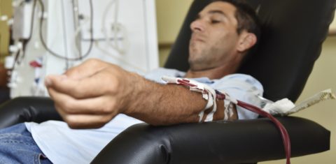 Foto colorida de pessoa recebendo transfusão de sangue. Ele é um homem branco, com cabelo curto preto, está sentado em uma cadeira no Centro de Hemodiálise do Hospital Regional de Sobradinho (HRS), no Distrito Federal.