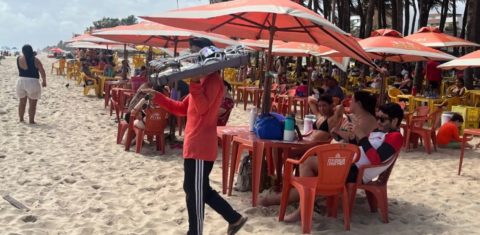 Ambulante vende óculos na Praia do Futuro: trabalho sem infraestrutura de apoio e com calor cada vez mais extremo (Foto: Lavínia Fonseca)